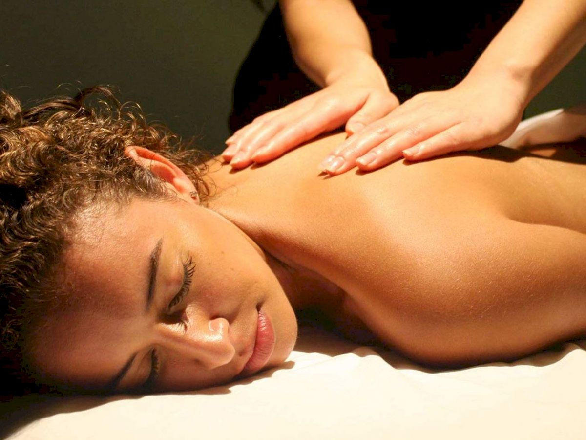 A person is lying on a massage table receiving a back massage from a therapist, creating a relaxed and calming atmosphere.