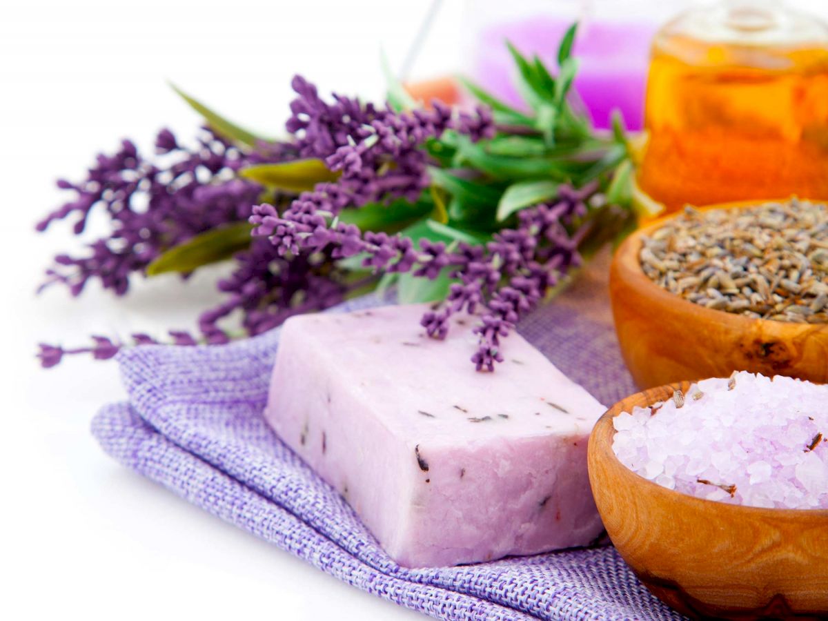 Lavender-themed spa items including lavender flowers, a lavender soap bar, a bowl of lavender buds, bath salts, and scented oil.