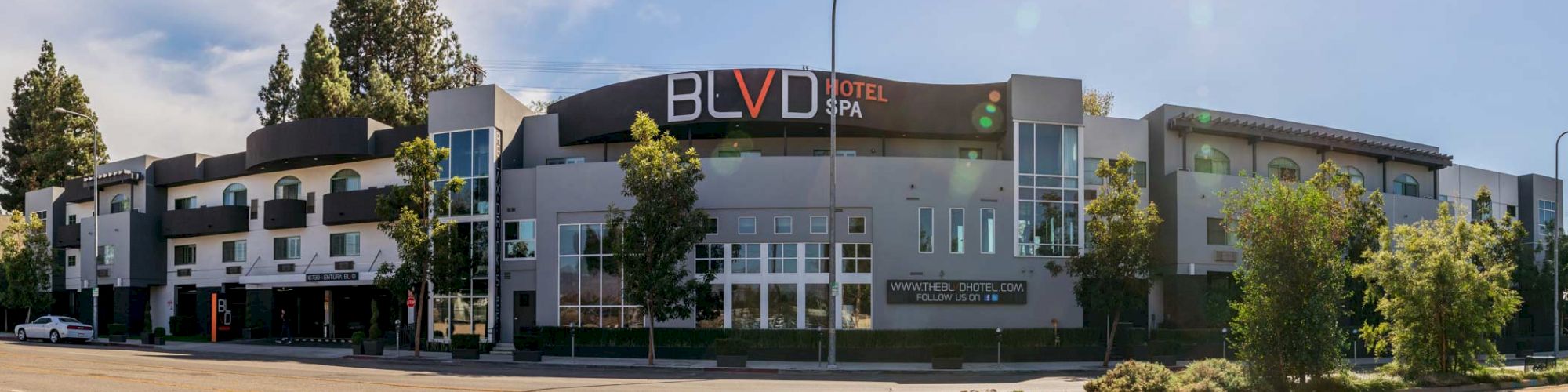 This image shows a modern hotel building with a sign reading 