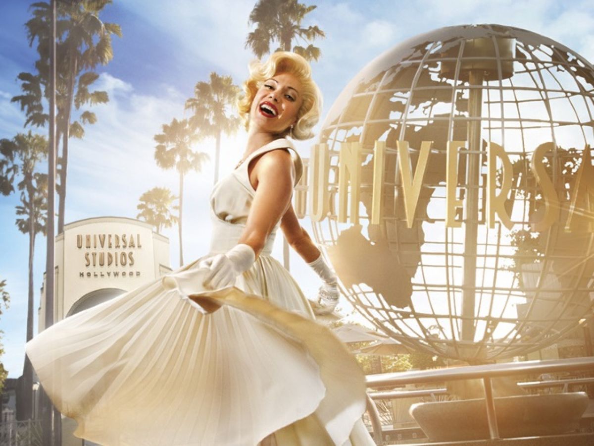 A woman in a white dress poses playfully with the Universal Studios globe and palm trees in the background, capturing a classic Hollywood vibe.