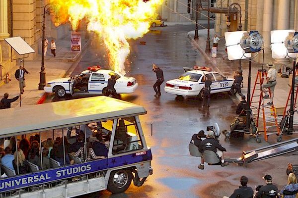 A movie scene with an explosion, police cars, and crew members, captured on a film set at Universal Studios.